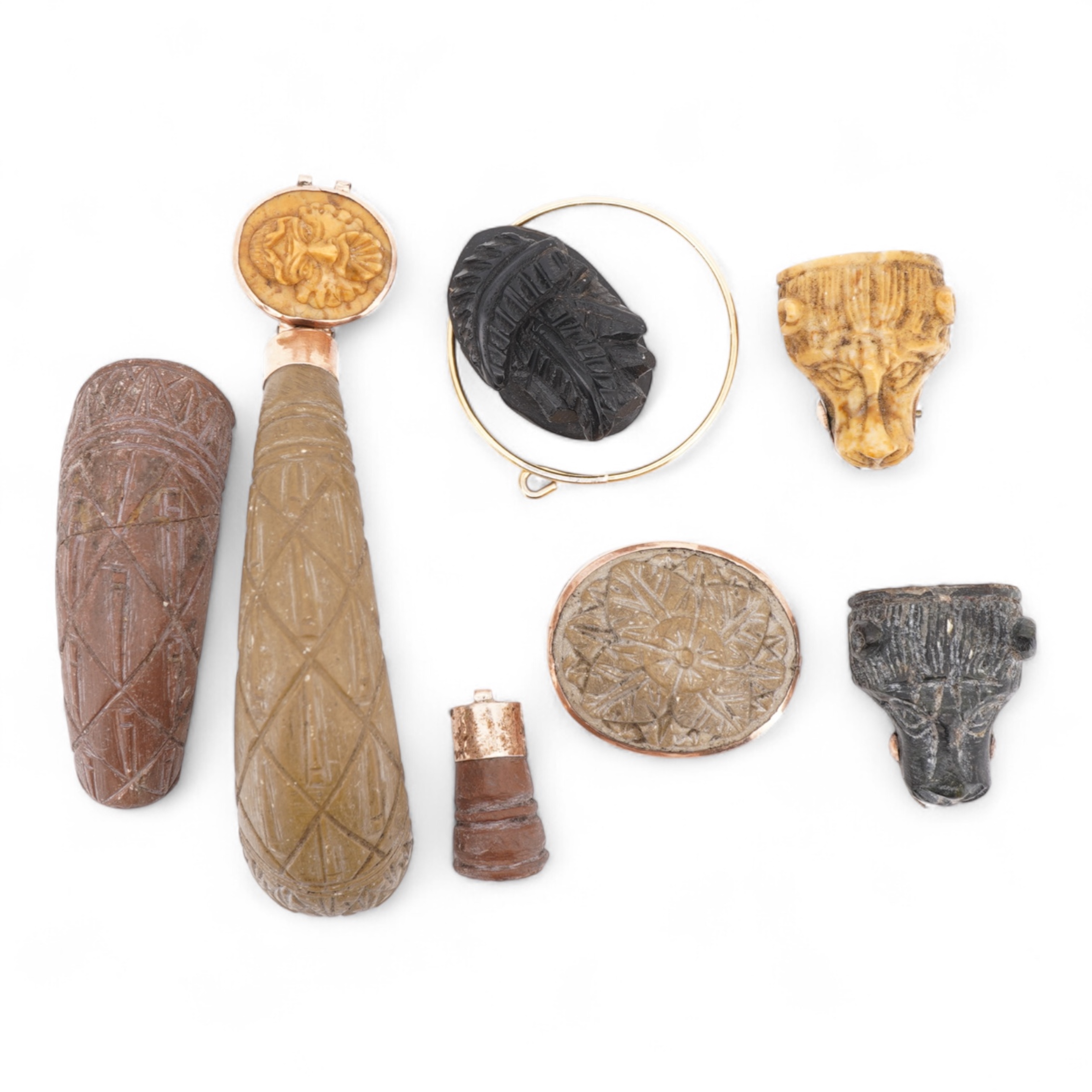 A collection of carved lava fragments, 19th century, once forming a bangle, the fragments variously carved with abstract floral motifs, lion's heads, and a theatrical mask, largest 6.2cm, Condition: fragmentary, but carv